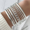 A stack of silver twisted bangle bracelets worn on a wrist.