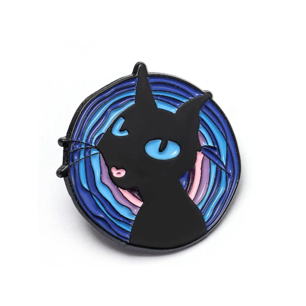 Broche émail noire avec des yeux bleus et des accents violets sur un fond bleu foncé.