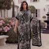 A woman models a black and white leopard zebra print maxi kaftan outdoors in front of a white building.