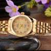 A luxury golden quartz wristwatch with a gold-toned band rests on a dark stone surface.