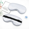 A pair of silver silk sleep masks with black straps are displayed next to a box labeled Chanel.