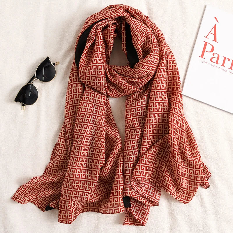 Luxuriöses Baumwoll-Pashmina-Schal mit rotbraunem geometrischem Muster, drapiert auf weißem Untergrund.