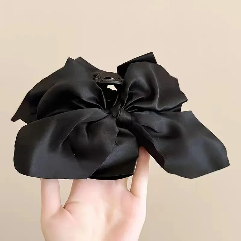 Pinza para el pelo de satén negro con diseño vintage de anacardo elegante, sostenida en una mano.