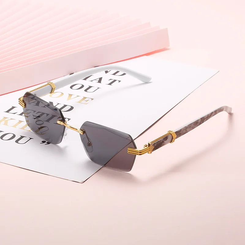 Gold-framed gradient sunglasses resting on a white card against a pink background.