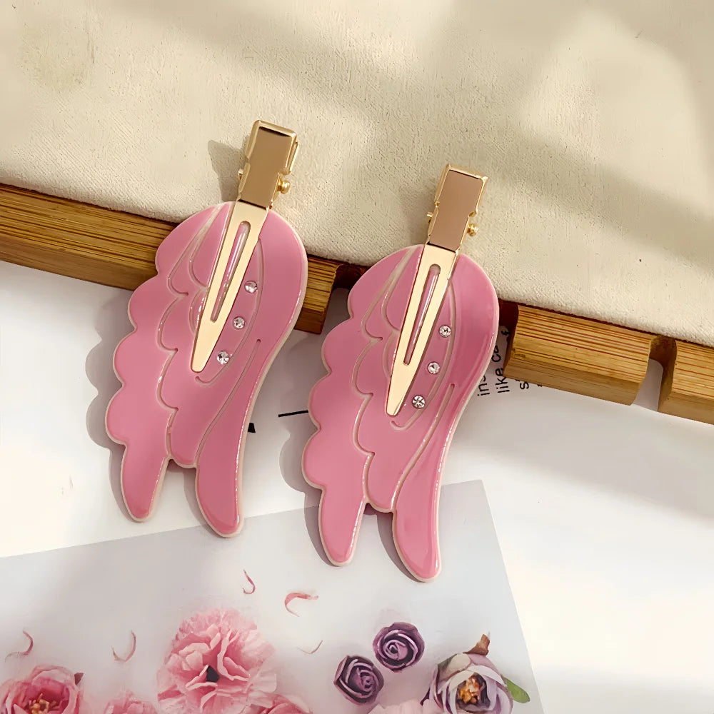 Pink angel wing hair clips and barrettes with gold accents displayed on a white background.