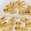 A collection of gold-colored metal hair rings and clips scattered on a white surface.