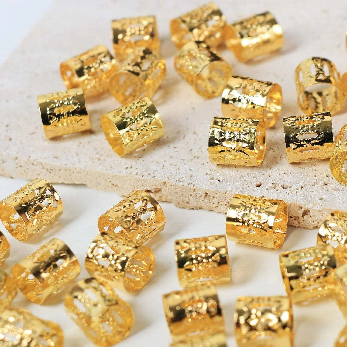 A collection of gold-colored metal hair rings and clips scattered on a white surface.