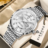 A silver and black Luminous Quartz wristwatch with a metal bracelet resting on a light beige surface.