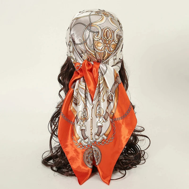 A luxurious satin silk scarf featuring an ornate gold and white pattern tied around dark hair.