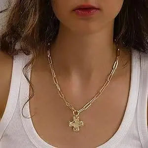 لقطة مقربة لامرأة ترتدي قلادة صليب ذهبي فضي سميكة على قميص أبيض.