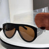 A pair of oversized black pilot sunglasses with brown lenses resting on a white surface.