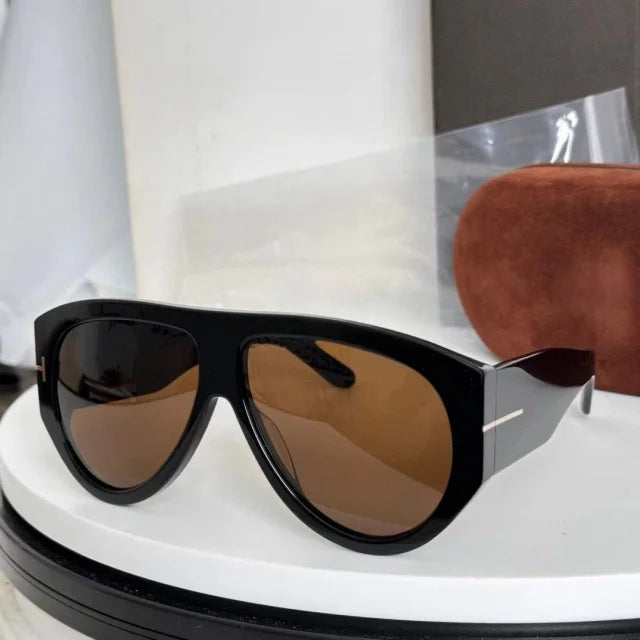 A pair of oversized black pilot sunglasses with brown lenses resting on a white surface.