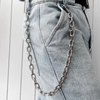 Nahaufnahme von hellgrauen Jeans mit silberner Kettengarnitur am Bund.
