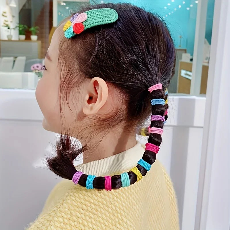 A young girl shows off her dark hair styled with colorful nylon elastic hair cords and a floral headband.