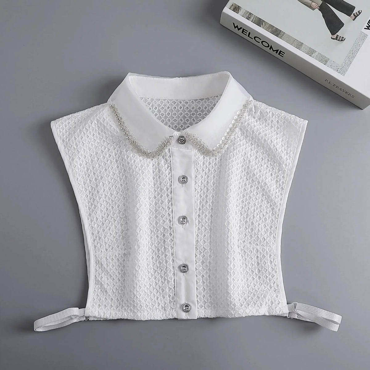 White blouse with a false collar and button-down front, displayed on a gray background.