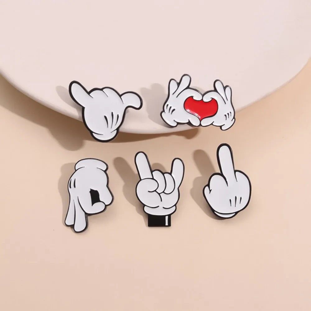 A set of enamel pins depicting various cartoon finger gestures, including a heart shape.