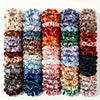 A set of five satin hair scrunchies in various shades of pink, purple, green, and brown.
