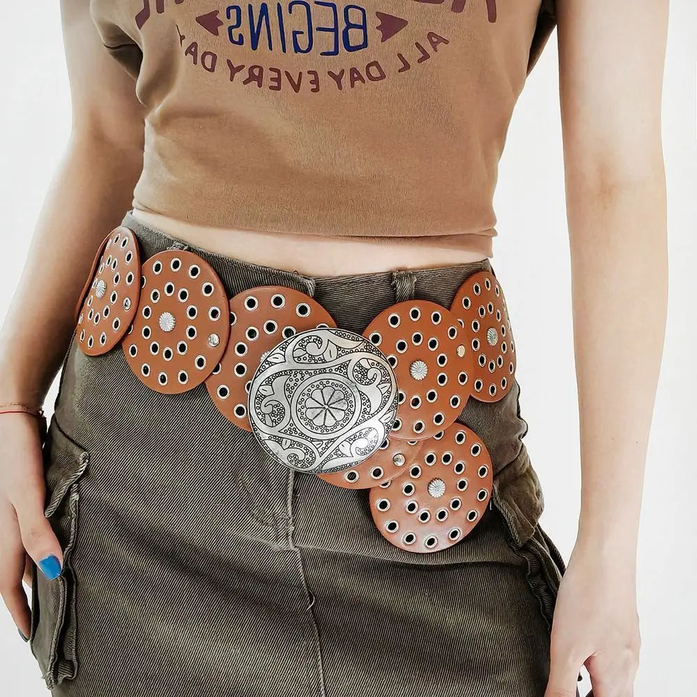 A close-up of a brown top and olive green skirt featuring vintage PU disc belts with metal buckles.
