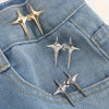 A pair of silver star-shaped decorative waist buckle buttons resting on a blue denim fabric.