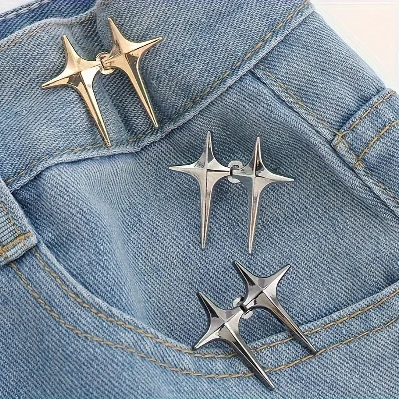 A pair of silver star-shaped decorative waist buckle buttons resting on a blue denim fabric.