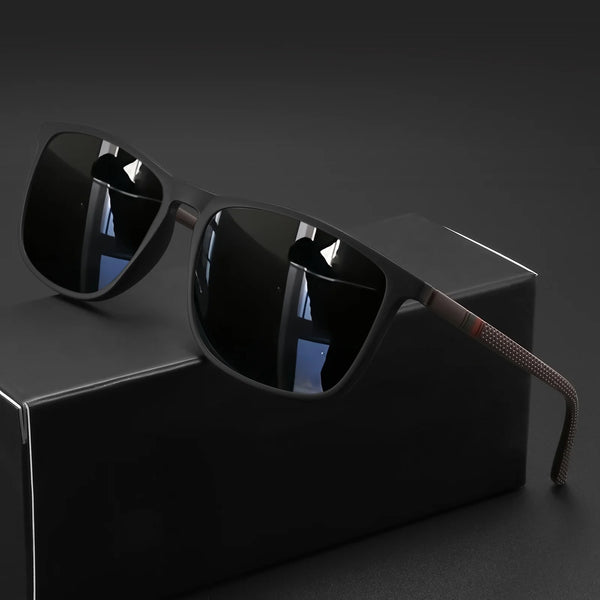 A pair of classic square sunglasses with dark lenses and a brown frame resting on a black box.