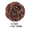 A round, textured brown hair bun clip-in featuring wispy curls and small clear accents.
