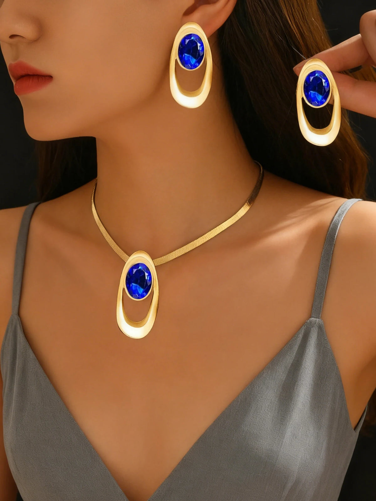 Gold and blue gemstone necklace set featuring an oval pendant and matching hoop earrings