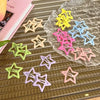 A collection of yellow, pink, and blue star-shaped hair clips displayed on a clear glass surface.