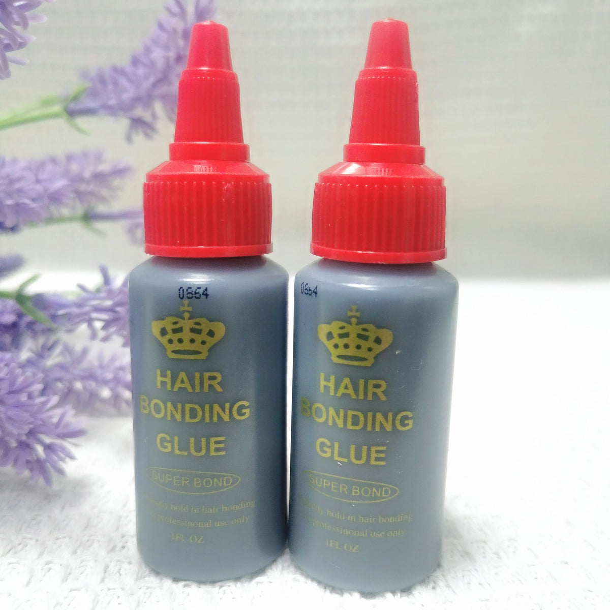 Two bottles of Hair Bonding Glue in a dark blue-gray liquid with red caps