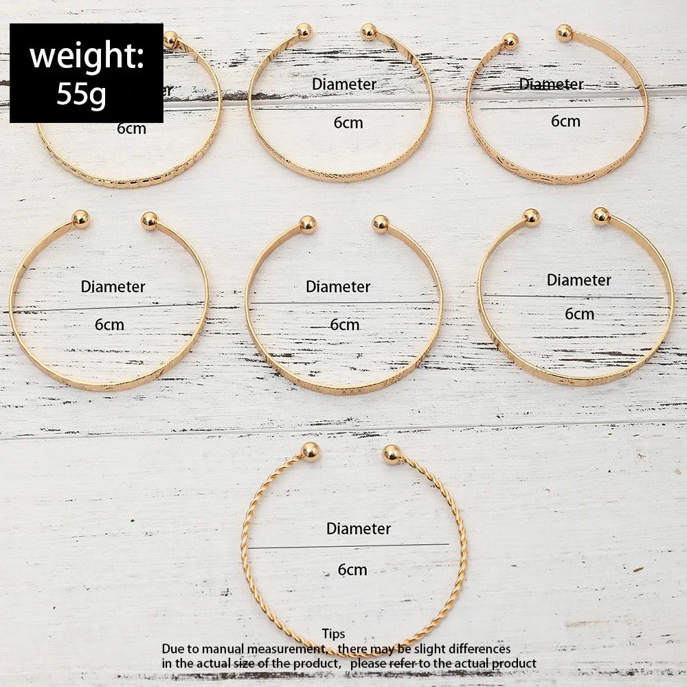 A set of gold hexagon star twist bangles shown in various sizes and angles on a white wooden background.