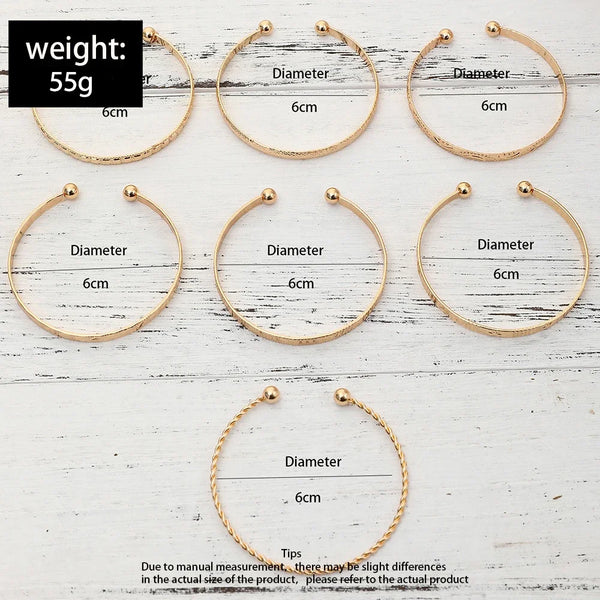 A set of gold hexagon star twist bangles shown in various sizes and angles on a white wooden background.