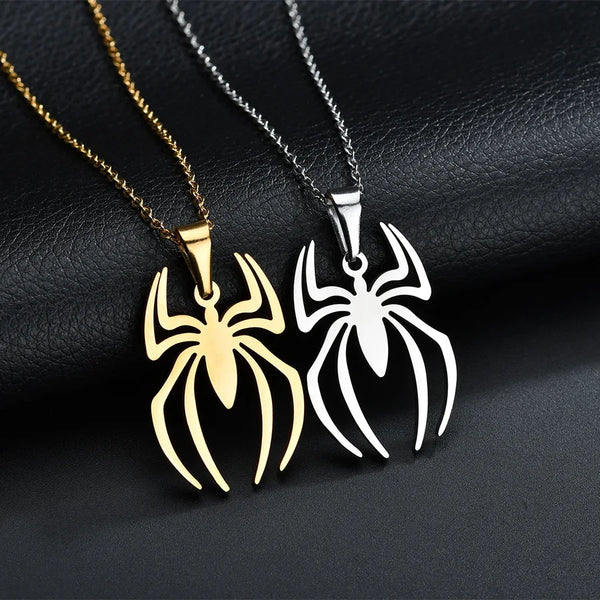 A pair of stainless steel spider pendant necklaces, one gold-toned and one silver-toned, displayed on a dark surface.