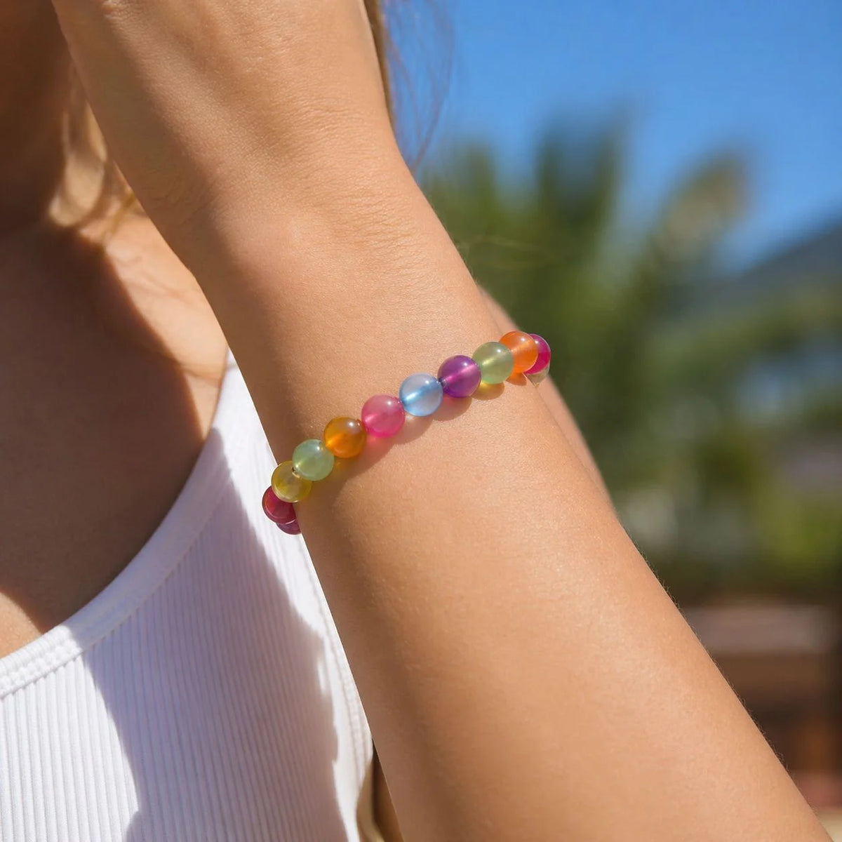 Handgelenk mit einem Strang UV-reaktiver Perlen in verschiedenen Farben vor hellem Außenhintergrund