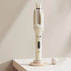 A white professional automatic curling iron with a vertical design resting on a wooden base.