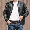 A man wearing a black leather jacket, white t-shirt, and dark jeans with a brown belt.