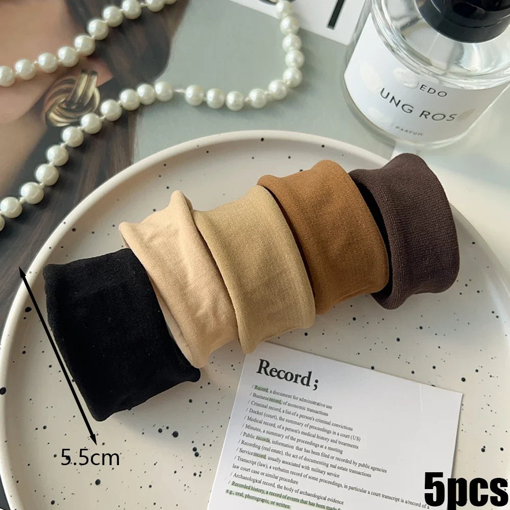 A collection of five extra-wide elastic hair bands in various earth tones, including black, tan, and brown.