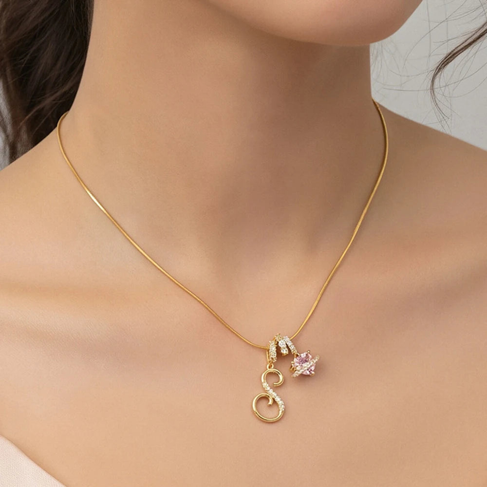 A delicate gold chain necklace with a personalized letter pendant featuring a pink gemstone.