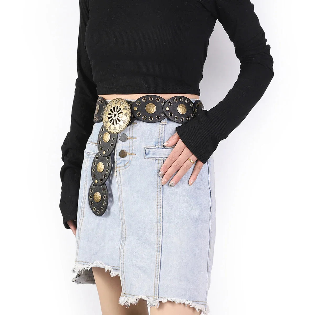 A light wash denim skirt paired with a round hollow metal belt featuring decorative studs and a black long-sleeved top.
