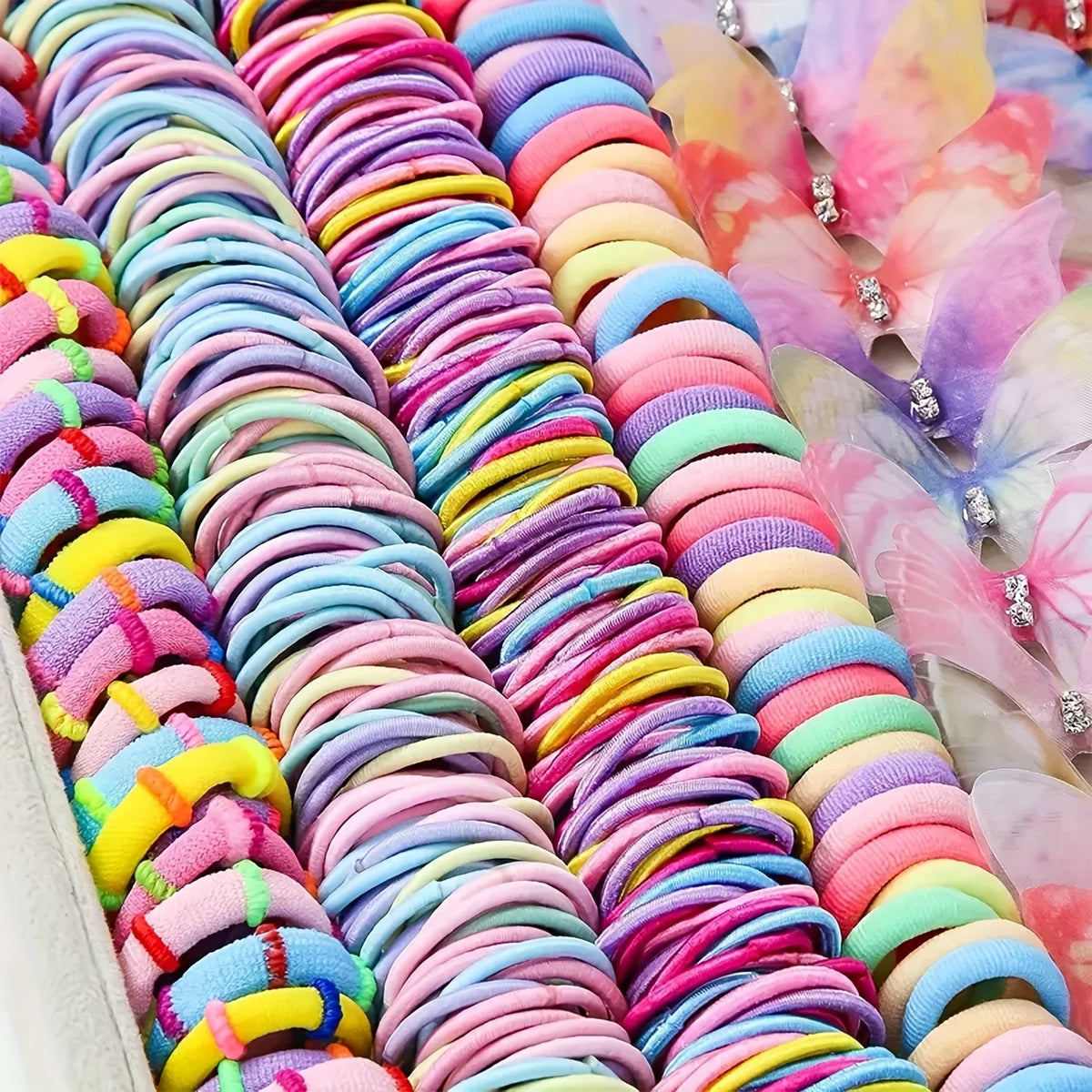 A close-up of a colorful decorative hair accessories set featuring stacked, coiled pink, purple, and blue hair ties.