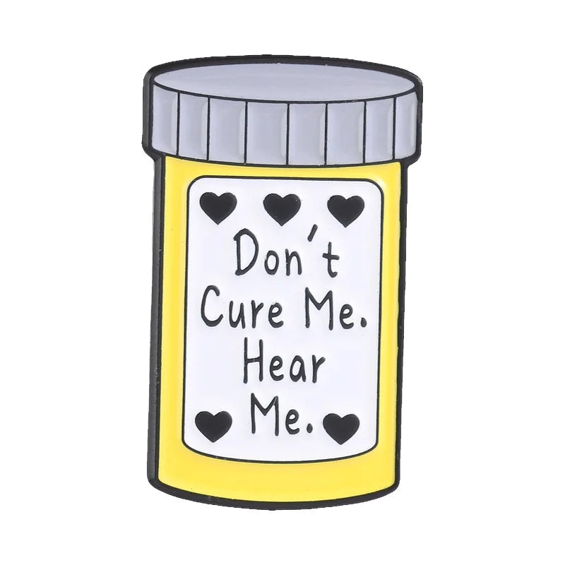 A yellow enamel pin featuring the black text Don't Cure Me Hear Me.