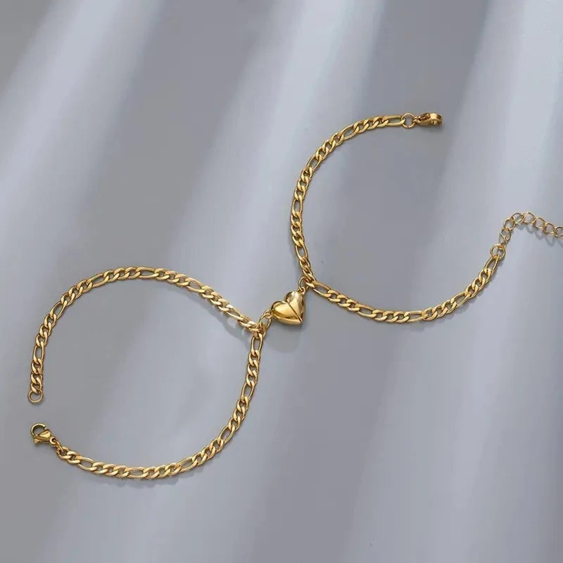A gold-colored stainless steel heart magnetic bracelet set for couples displayed against a gray background.