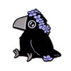 Schwarzer Email-Reversspieß mit einer Krähen-Silhouette, verziert mit violetten Blumen.