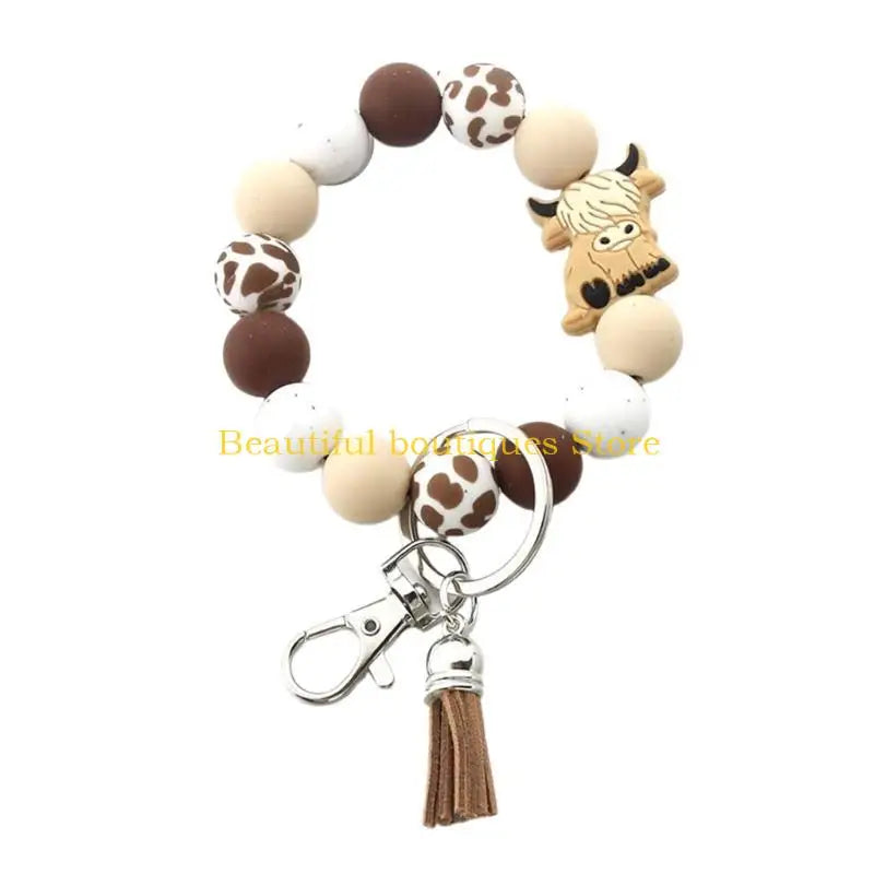 A silicone wristlet keychain featuring a decorative Highland cow design with various colored spherical charms.