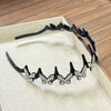 A black clip headband decorated with sparkling butterfly embellishments displayed in a light-colored box.