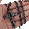 Colgante de cruz de acero inoxidable con cadena negra mostrado en la mano de una persona.