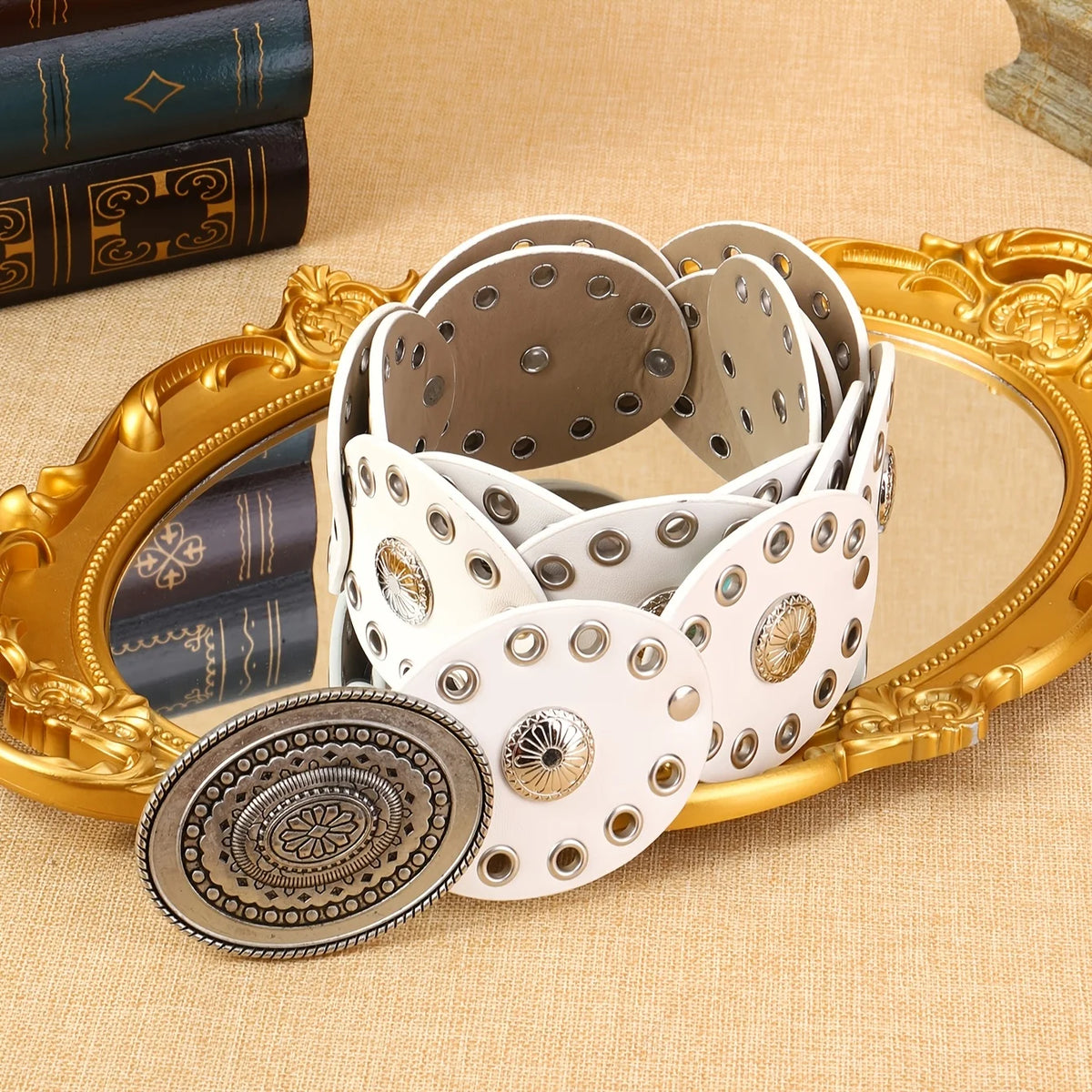 A collection of white and gold floral oval waist belts displayed on a decorative gold tray.