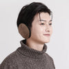 A close-up profile shot of a person wearing brown knitted earmuffs for cold weather protection.