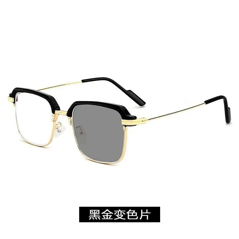 Une paire de lunettes de lecture photochromiques noires avec des accents dorés sur fond blanc.