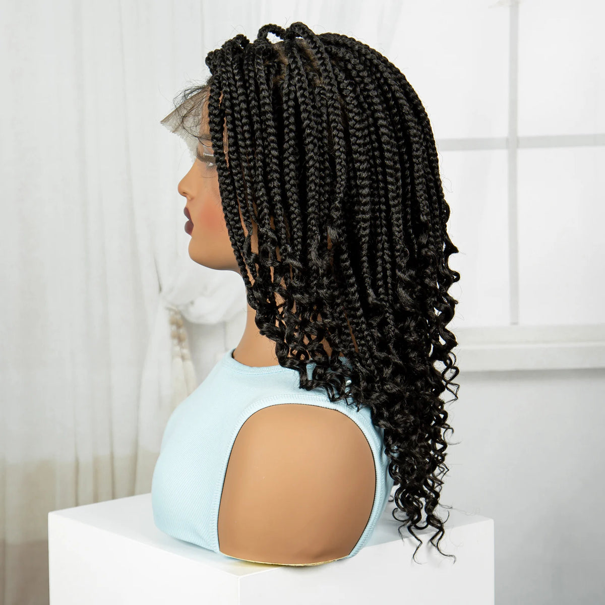 A woman models a black box braid wig with a light blue top against a white background.