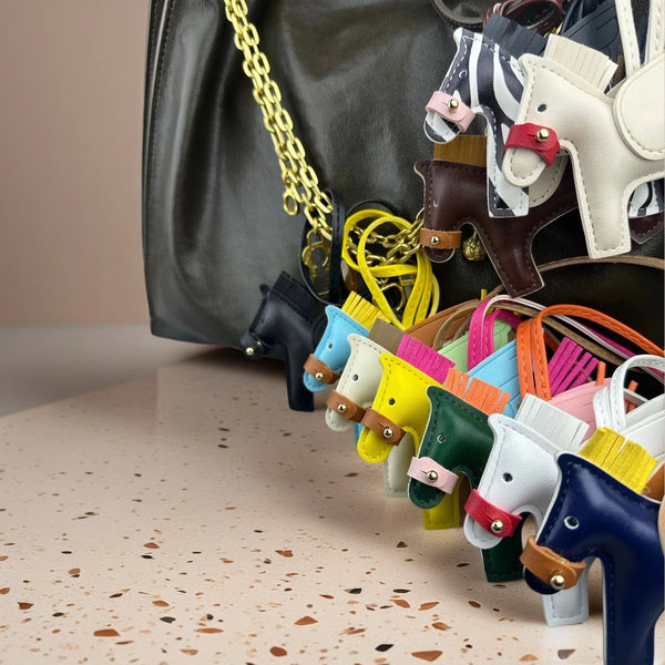 A close-up of an elegant winged pony keychain featuring various colored leather and fabric accents.